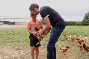 un agriculteur aidant un enfant à prendre une poule